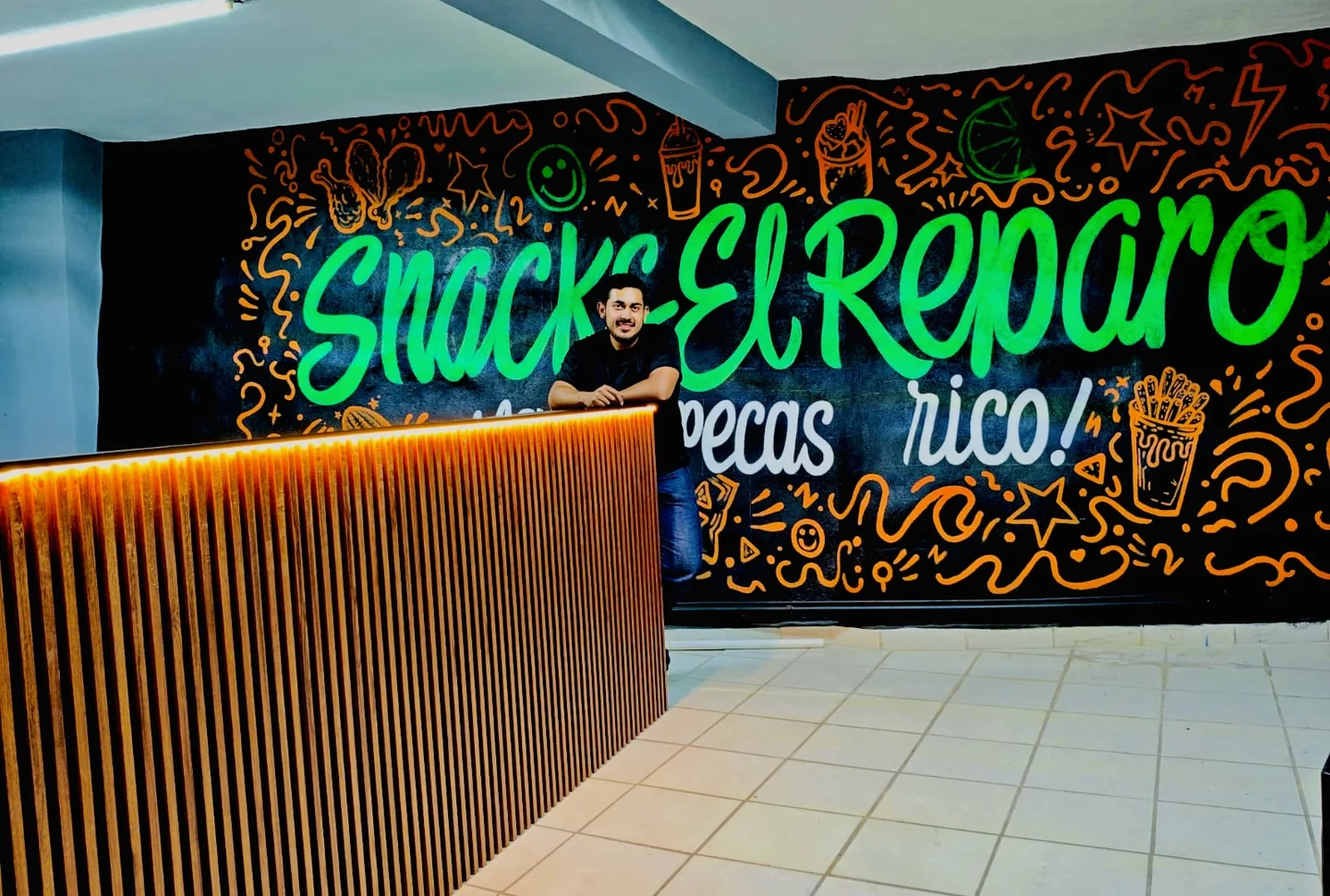 Interior real de Snacks El Reparo con mural negro, verde y naranja